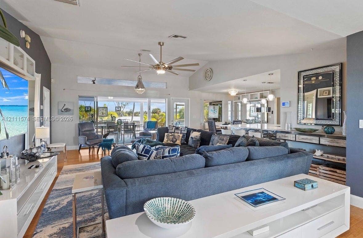 Open-concept living area featuring vaulted ceilings, recessed lighting, a modern ceiling fan, and large sliding glass doors leading to a covered patio
