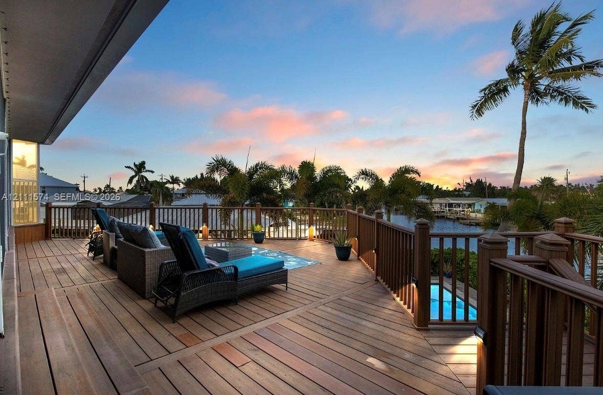 Expansive wood-plank deck featuring a wrap-around railing, integrated low-voltage lighting, and direct water access