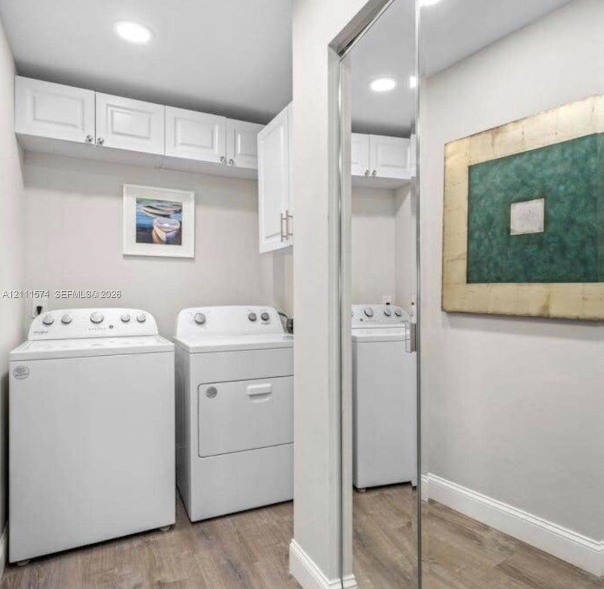 Laundry space featuring white shaker-style wall cabinetry, recessed ceiling lighting, and wood-finish flooring