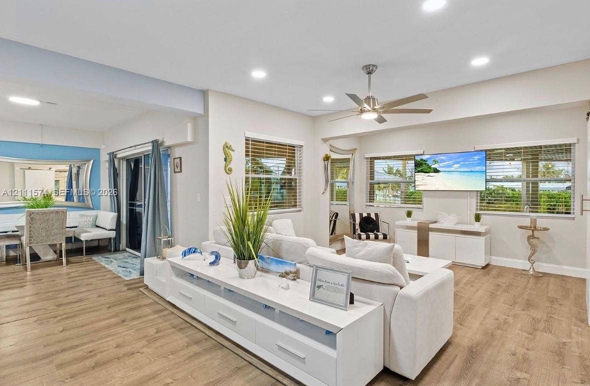 Open-concept room featuring wood-finish flooring, recessed lighting, a ceiling fan, and large windows with horizontal blinds