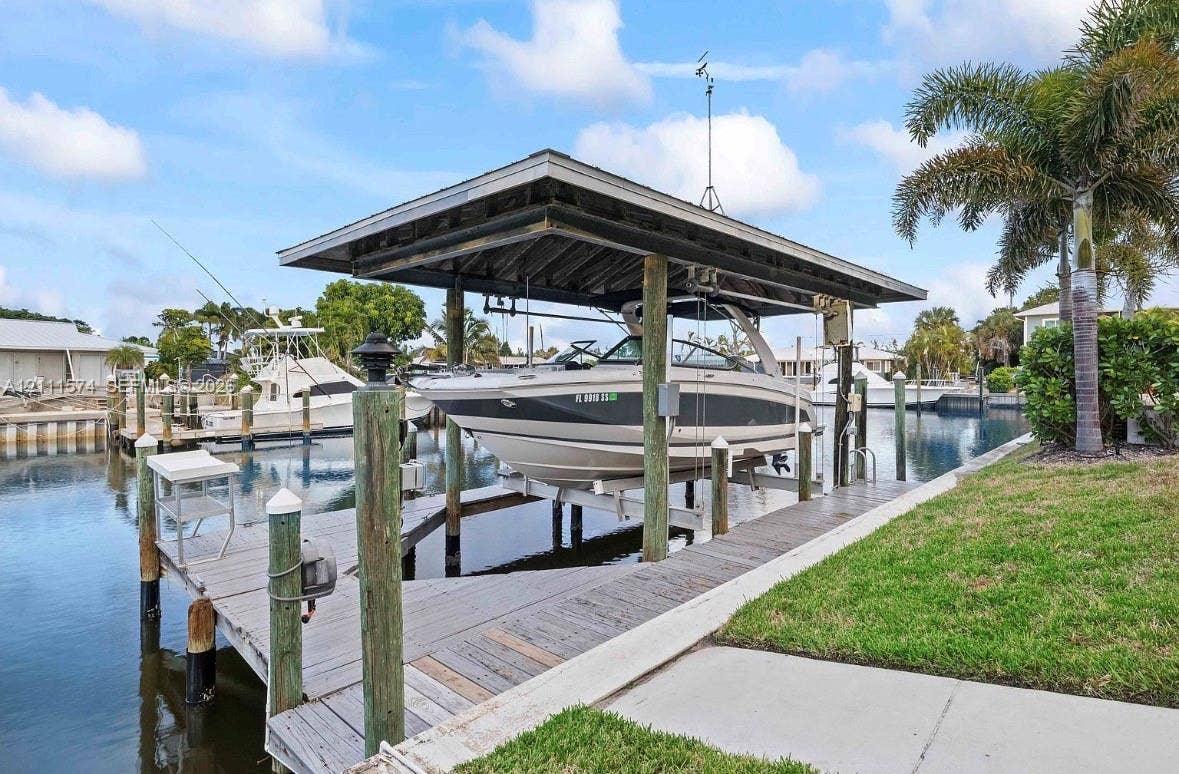 Private dock featuring a wooden deck, covered boat lift, and direct water access