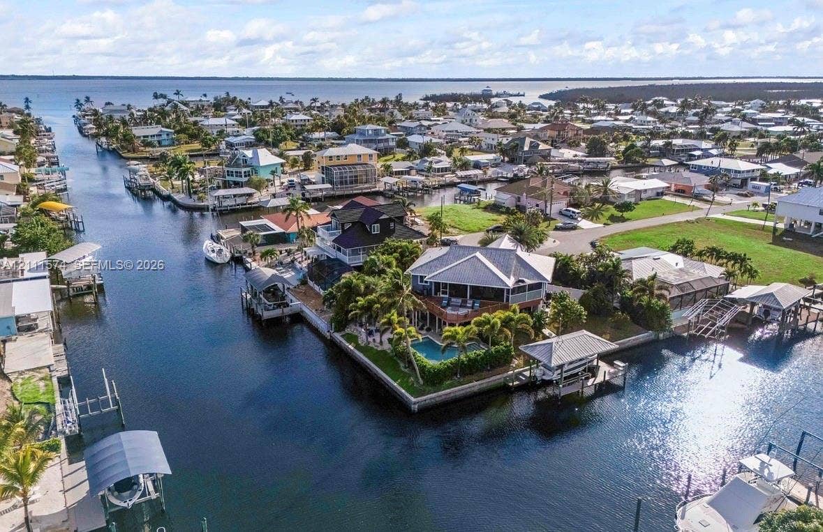 Waterfront property featuring a private swimming pool, deep-water canal access, a boat lift, and a wrap-around balcony