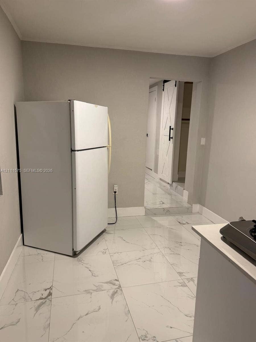 Large-format white stone-patterned tile flooring, white sliding barn-style door with dark hardware, and clean neutral wall finishes