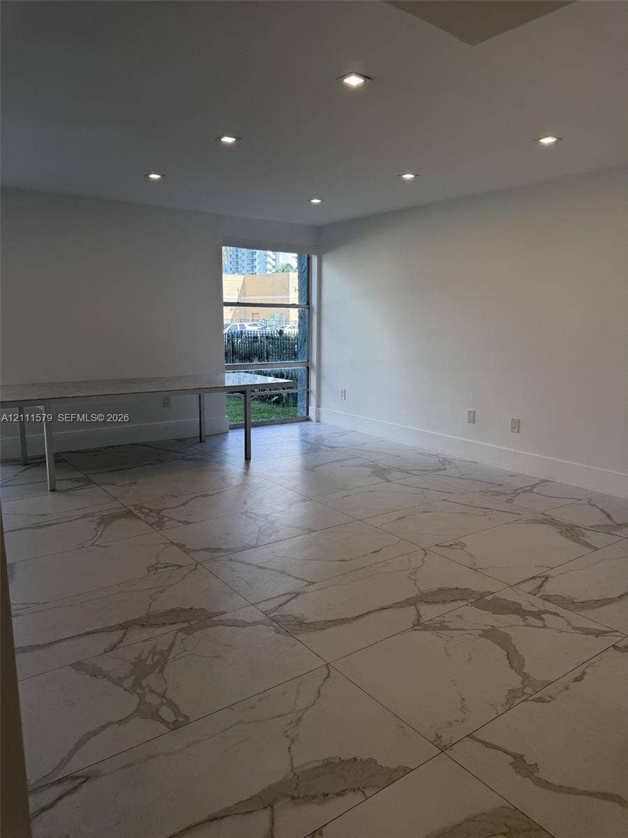 Large-format veined tile flooring, recessed ceiling lighting, and a tall picture window