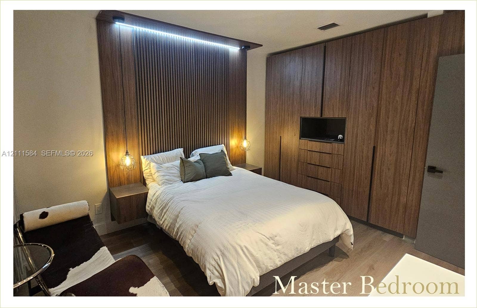 Wood-slat accent wall with integrated LED lighting, built-in floor-to-ceiling cabinetry, floating bedside tables, and wood-finish flooring