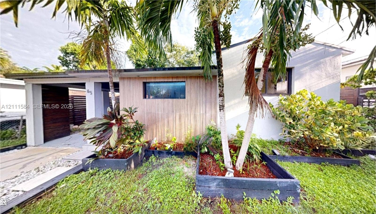 Exterior facade featuring wood-slat accent cladding, integrated carport, horizontal window, and raised landscape planters