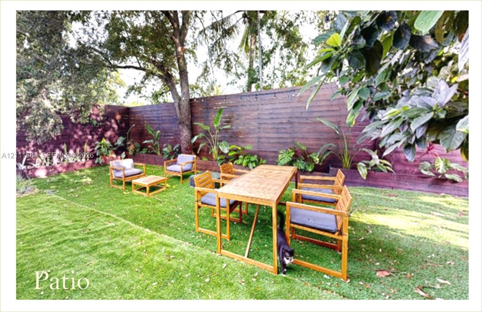 Private outdoor space featuring a horizontal wood slat fence, mature trees, and established perimeter landscaping