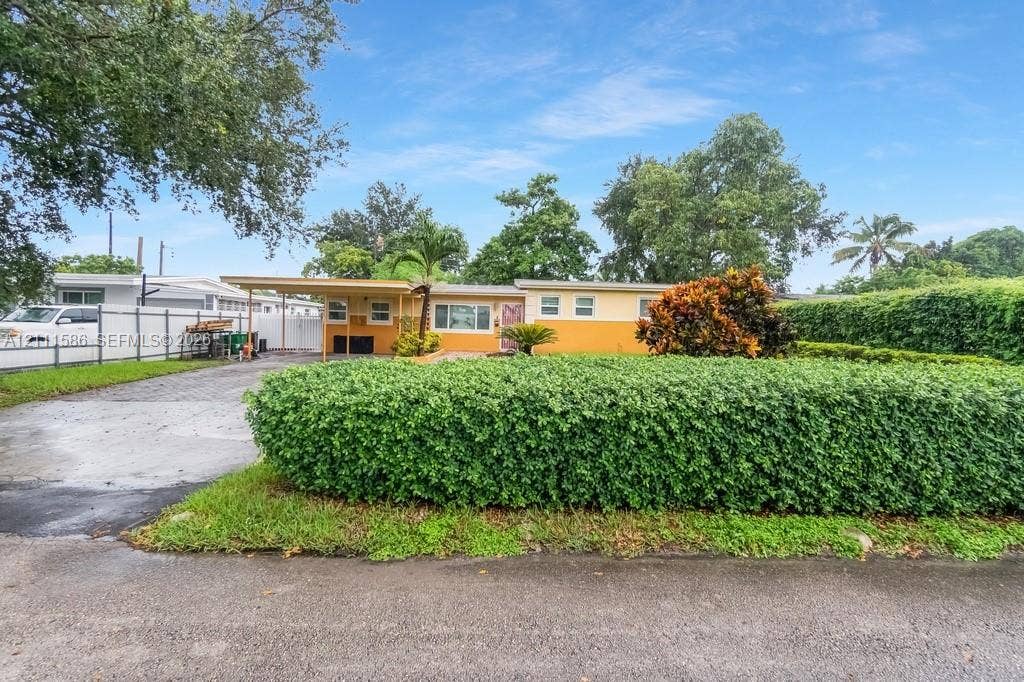 20431 NE 14th Court, Miami, FL 33179 Single-story residence featuring a paved driveway, attached carport, and a manicured hedge perimeter