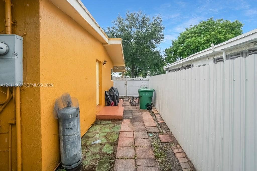 20431 NE 14th Court, Miami, FL 33179 Exterior side path featuring stone paver walkways and a tall vinyl privacy fence