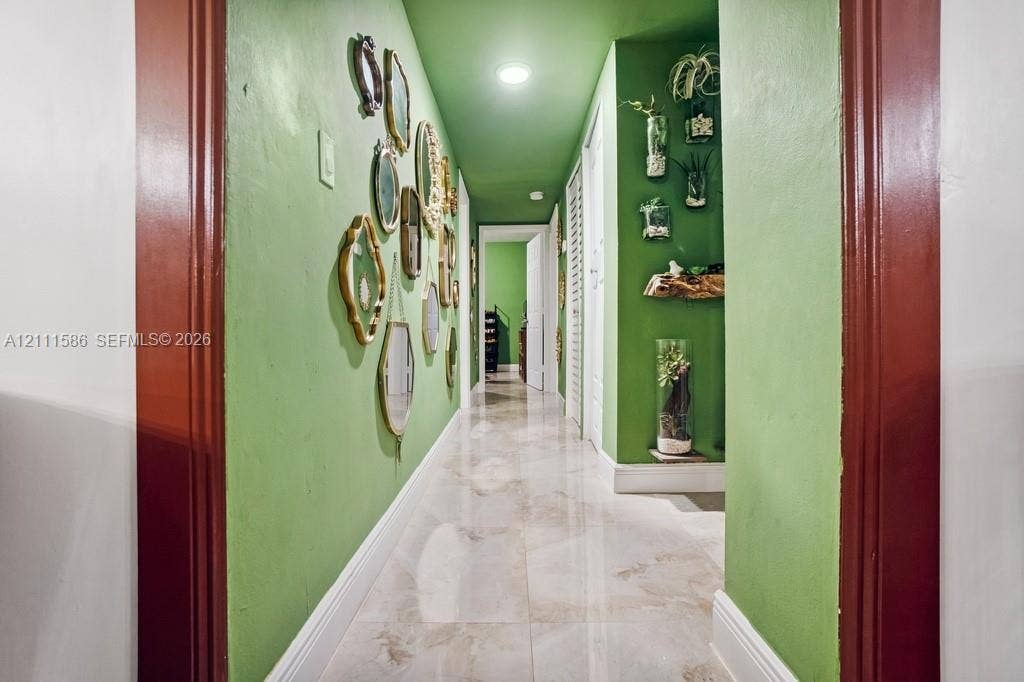 20431 NE 14th Court, Miami, FL 33179 Hallway featuring large-format polished tile flooring, recessed ceiling lighting, and custom millwork door casings finished in a deep red tone