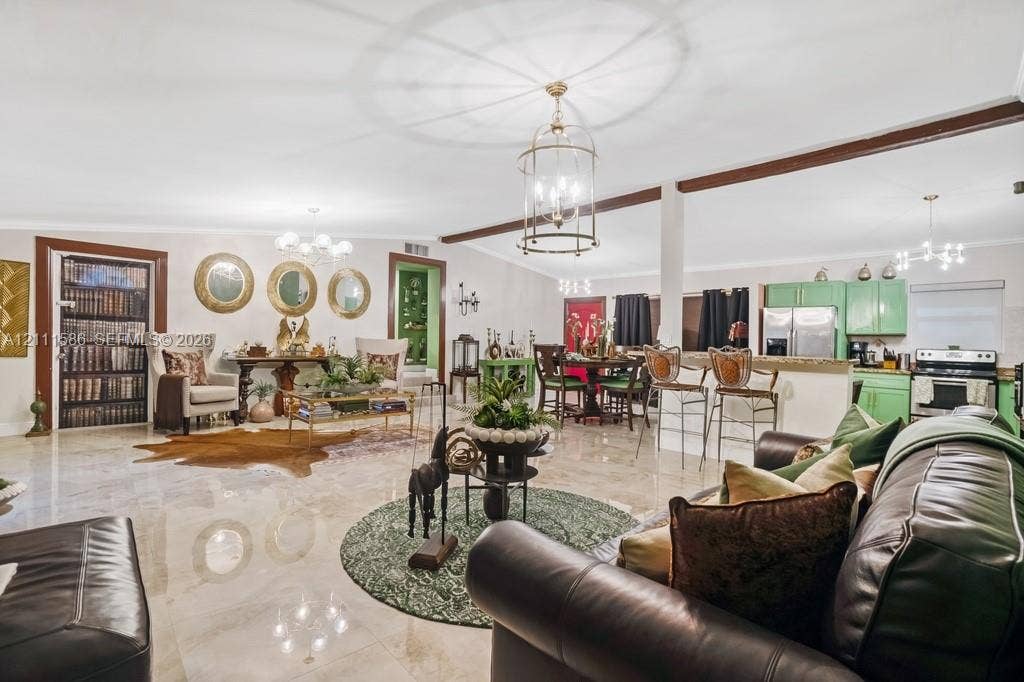 20431 NE 14th Court, Miami, FL 33179 Open-concept interior featuring large-format tile flooring, exposed ceiling beams, custom green cabinetry, stone-surface breakfast bar, and ornate multi-light pendant fixtures