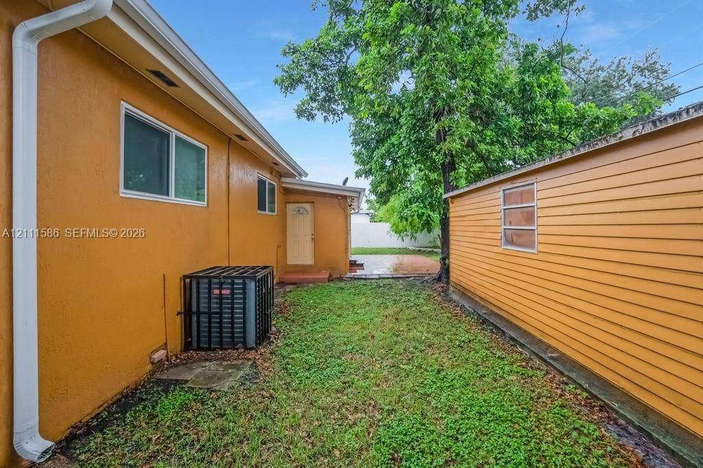 20431 NE 14th Court, Miami, FL 33179 Exterior side yard featuring stucco and horizontal siding finishes, mature trees, and a detached structure
