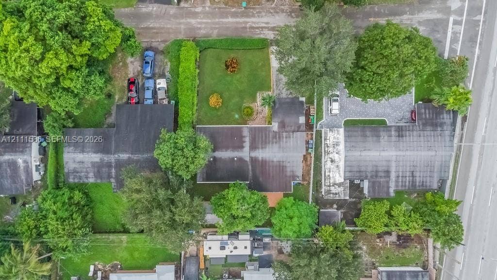 20431 NE 14th Court, Miami, FL 33179 Aerial perspective featuring a manicured lawn, paved driveway, mature trees, and shingled roof structures
