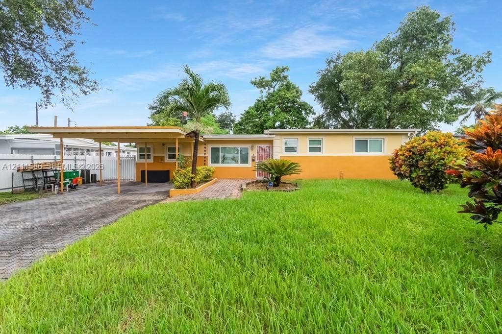 20431 NE 14th Court, Miami, FL 33179 Exterior facade featuring a two-tone stucco finish, covered carport, brick-paver walkway, and manicured lawn