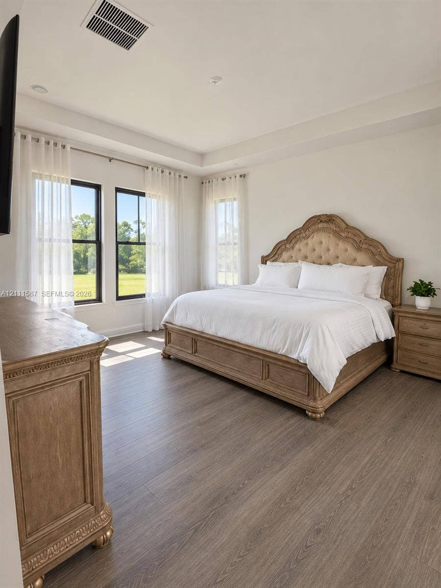 Tray ceiling, wood-finish flooring, and black-framed windows providing natural light