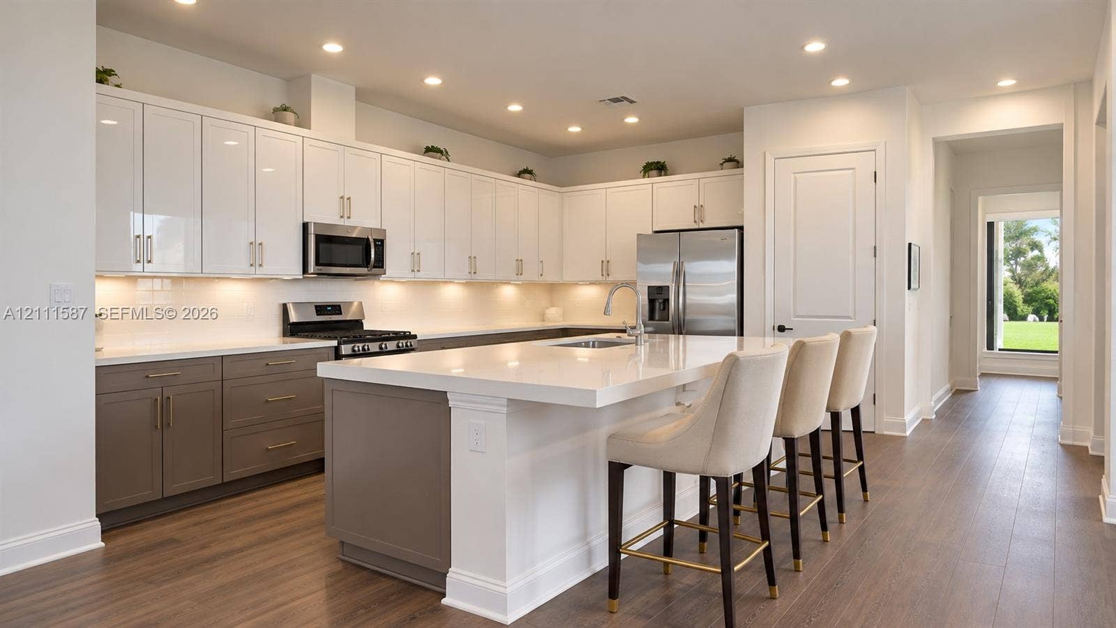 Kitchen featuring two-tone cabinetry, quartz countertops, central island, stainless steel appliances, and wood-finish flooring