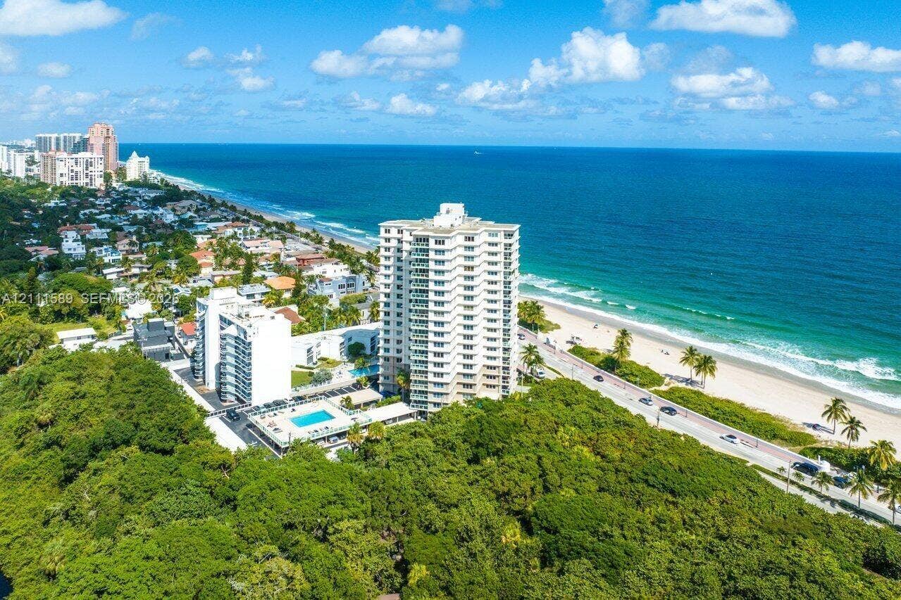 High-rise coastal residential building featuring private swimming pool, surrounding green space, and proximity to the shoreline