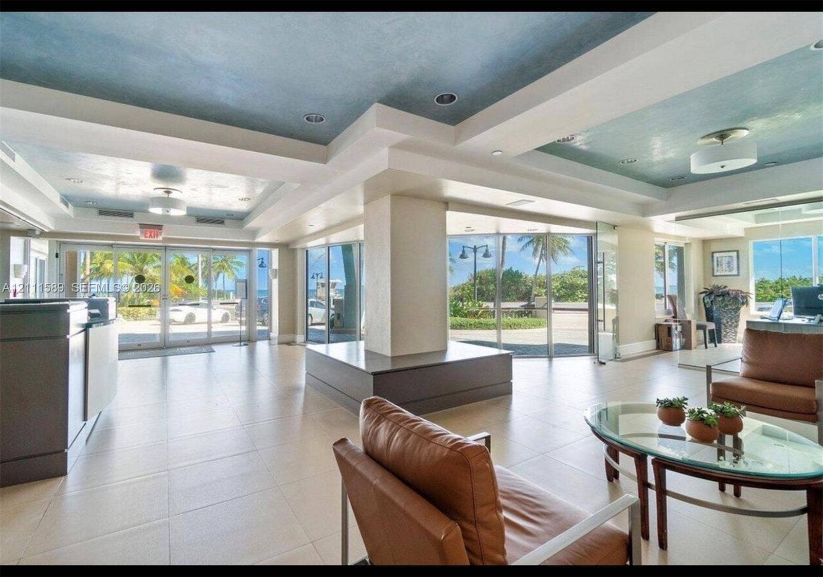 Lobby area featuring large-format tile flooring, recessed ceiling lighting, a textured blue ceiling finish, and expansive floor-to-ceiling glass paneling