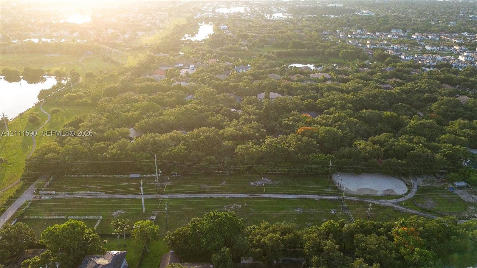 Aerial perspective of a sprawling parcel featuring expansive green space, mature tree canopy, and established landscaping
