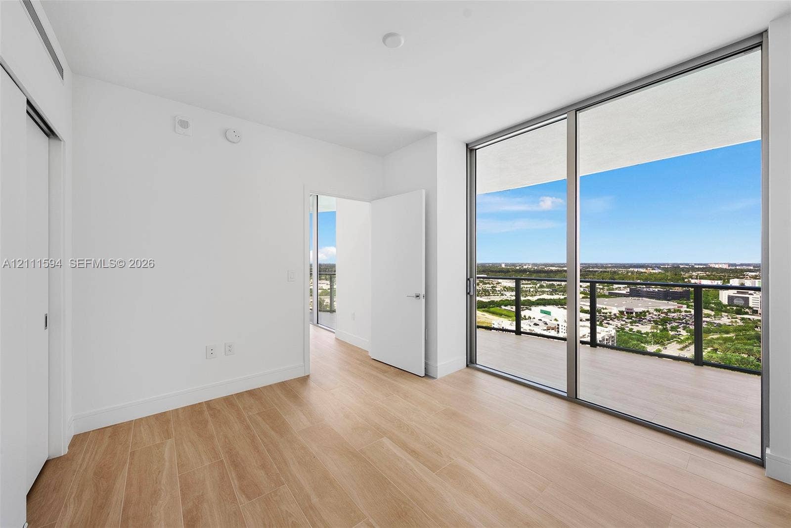 2411 Laguna Circle, #2506, North Miami, FL 33181 Floor-to-ceiling glass windows, private balcony with metal railing, wood-finish flooring, and crisp white wall finishes