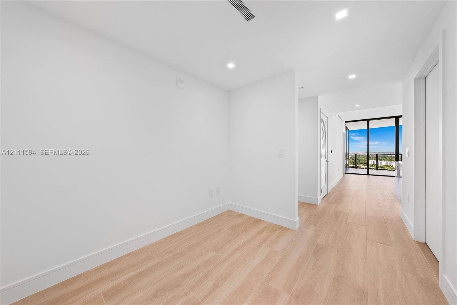 2411 Laguna Circle, #2506, North Miami, FL 33181 Interior space featuring light-toned wood-finish flooring, recessed ceiling lighting, and floor-to-ceiling glass sliding doors with balcony access