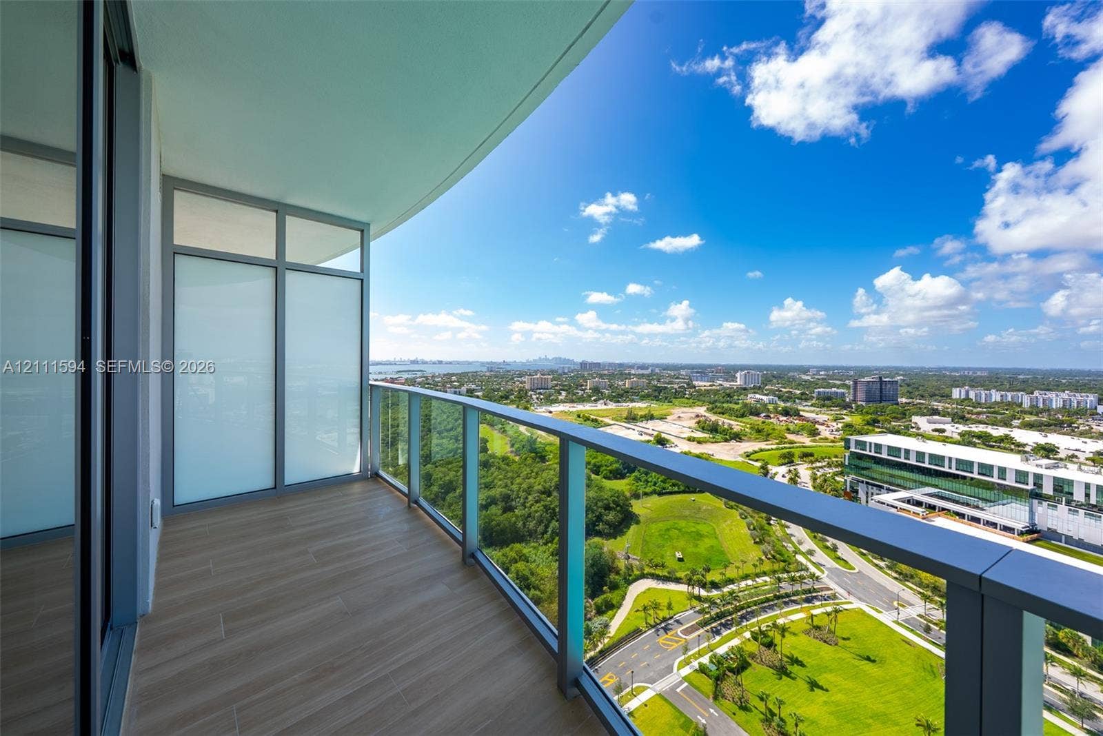 2411 Laguna Circle, #2506, North Miami, FL 33181 Covered balcony featuring wood-finish flooring, glass panel railings, and full-height exterior windows