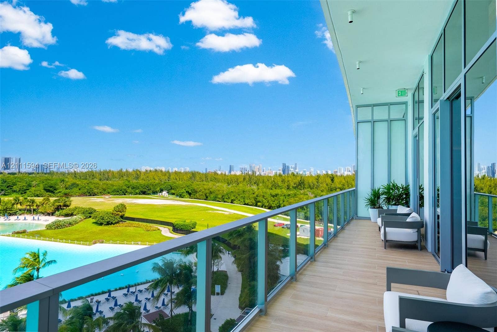 2411 Laguna Circle, #2506, North Miami, FL 33181 Covered balcony featuring wood-finish flooring, full-height glass panel railings, and floor-to-ceiling glass wall panels