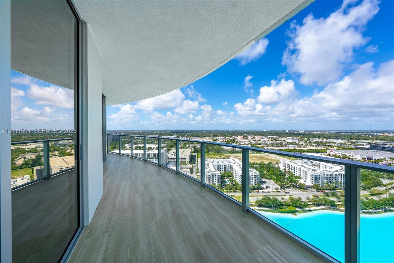 2411 Laguna Circle, #2506, North Miami, FL 33181 Curved balcony featuring wood-finish tile flooring, a glass panel railing, and expansive exterior scenery