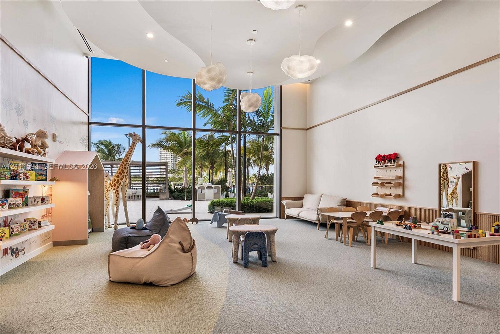 2411 Laguna Circle, #2506, North Miami, FL 33181 Floor-to-ceiling windows, custom sculpted ceiling with recessed lighting, integrated wall shelving, wood-paneled wainscoting, and suspended contemporary light fixtures