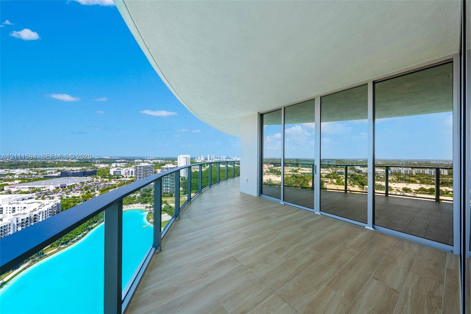 2411 Laguna Circle, #2506, North Miami, FL 33181 Expansive covered balcony featuring tile flooring, metal railing, and floor-to-ceiling glass panel doors