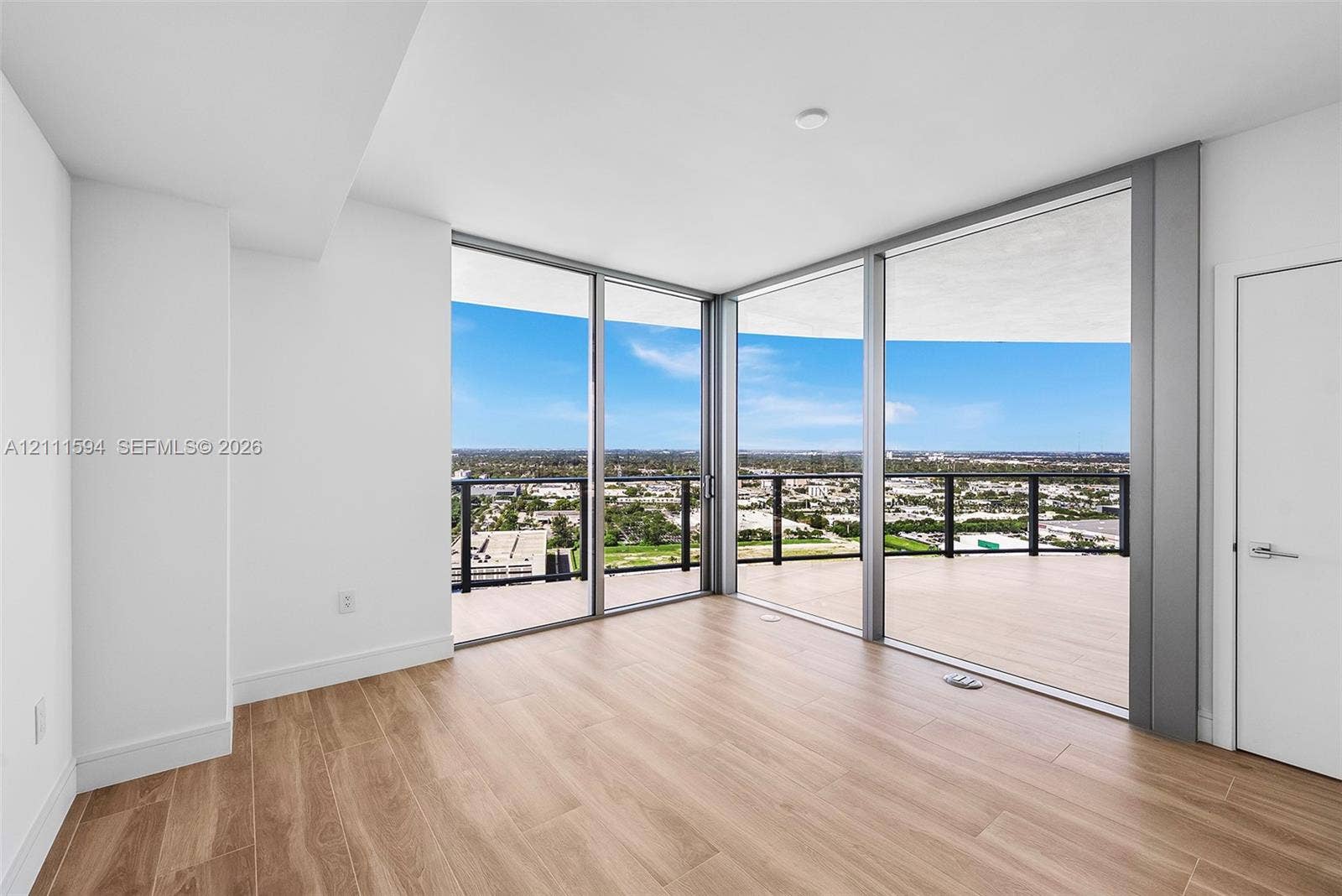2411 Laguna Circle, #2506, North Miami, FL 33181 Floor-to-ceiling glass corner walls, wood-finish flooring, and expansive wrap-around balcony with metal railings