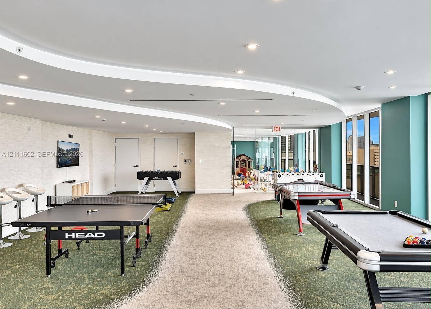 Expansive interior space featuring a curved dropped ceiling, recessed lighting, floor-to-ceiling windows, and dual-textured carpeting