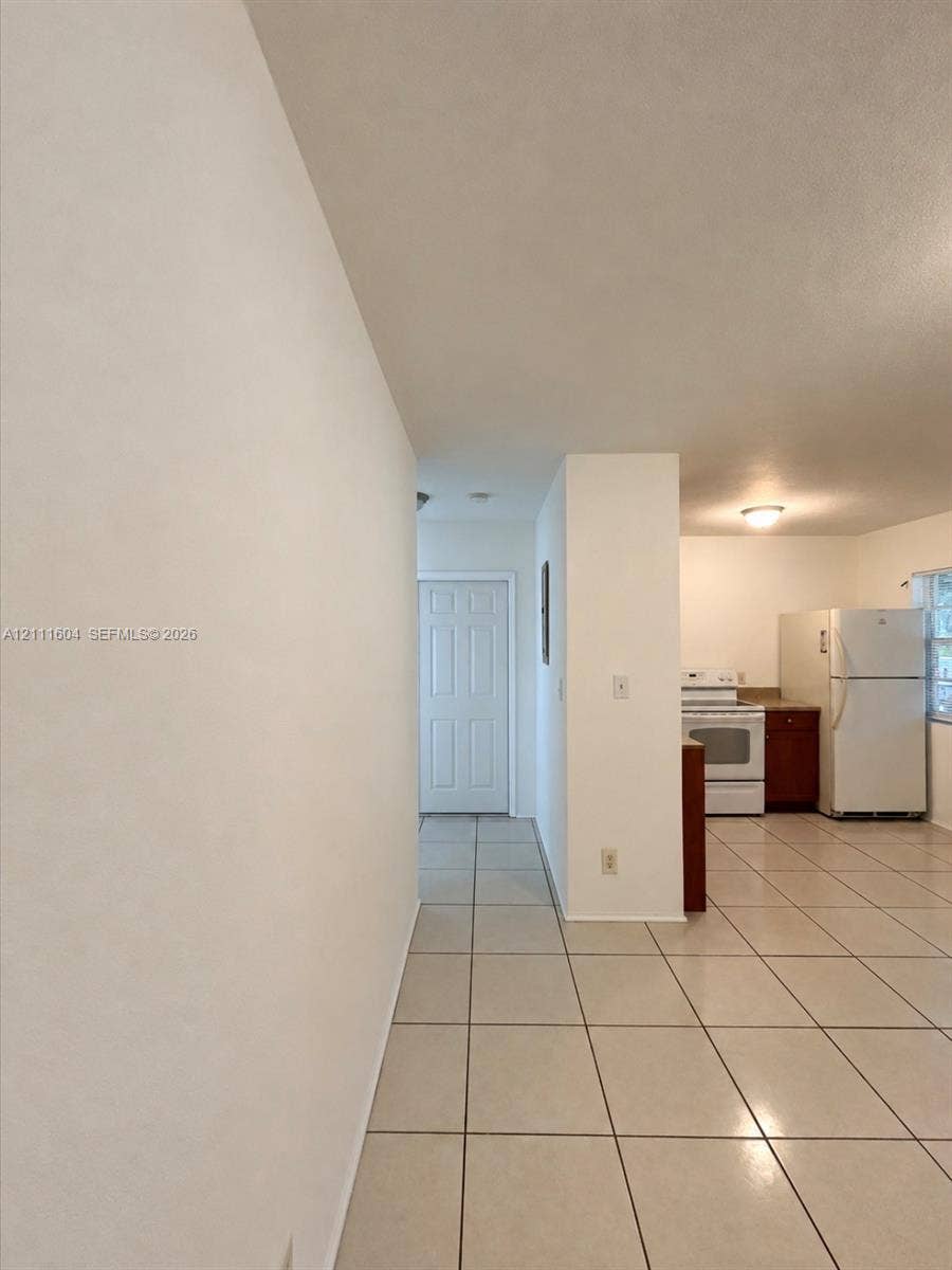 Ceramic tile flooring, white-finish cabinetry, and a six-panel interior door