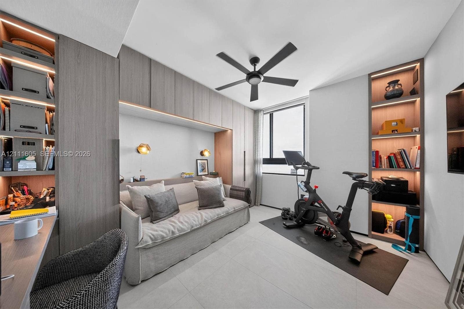 Custom floor-to-ceiling wood-finish cabinetry with integrated LED lighting, recessed wall-mounted reading sconces, and a multi-speed ceiling fan