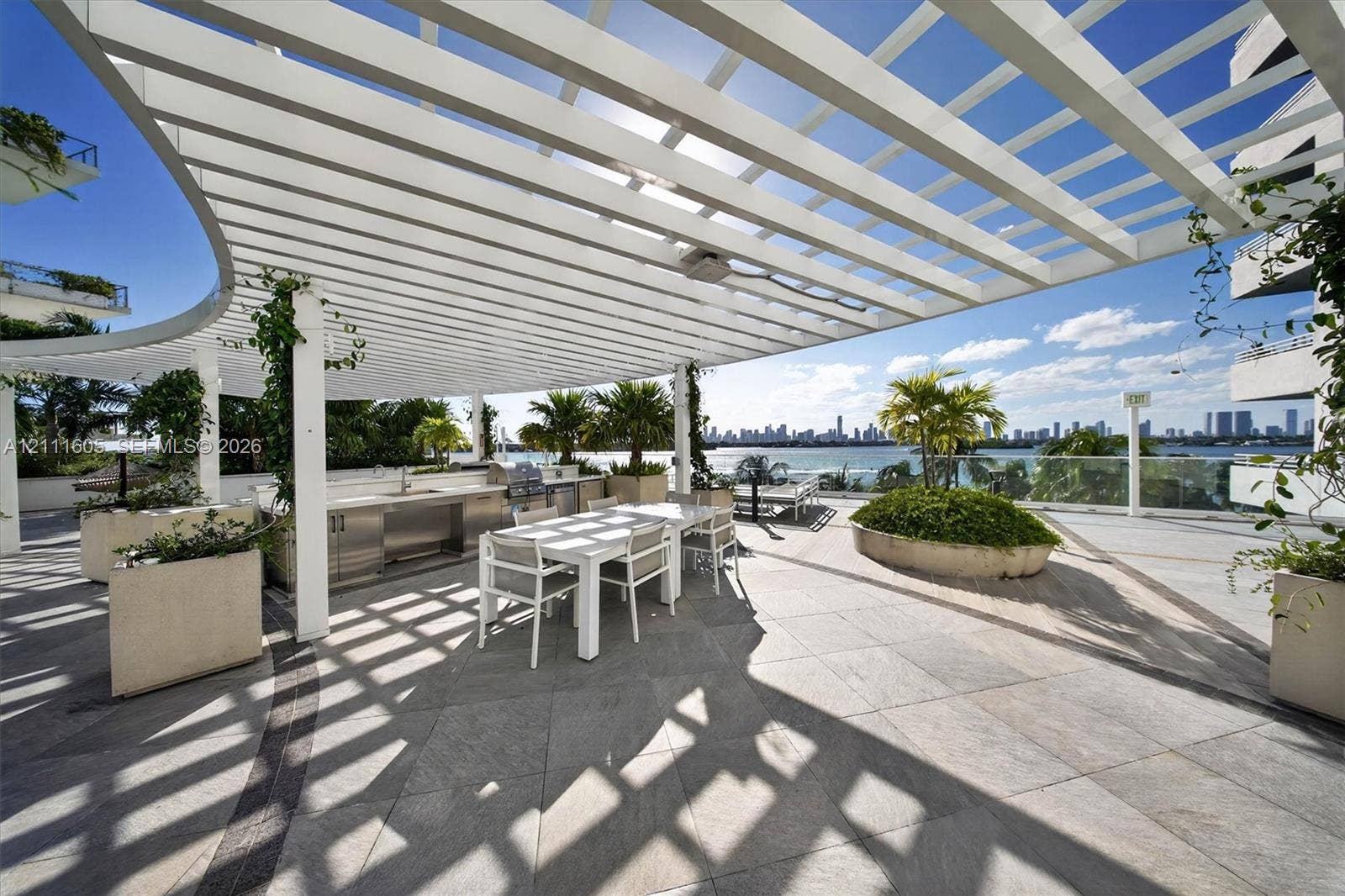 High-rise residential tower featuring a white facade, landscaped podium-level terrace, ground-level swimming pool, and water-front placement