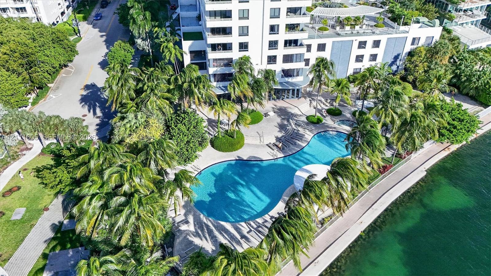 Waterfront property featuring a concrete seawall, stone-paver hardscaping, and a skyline horizon