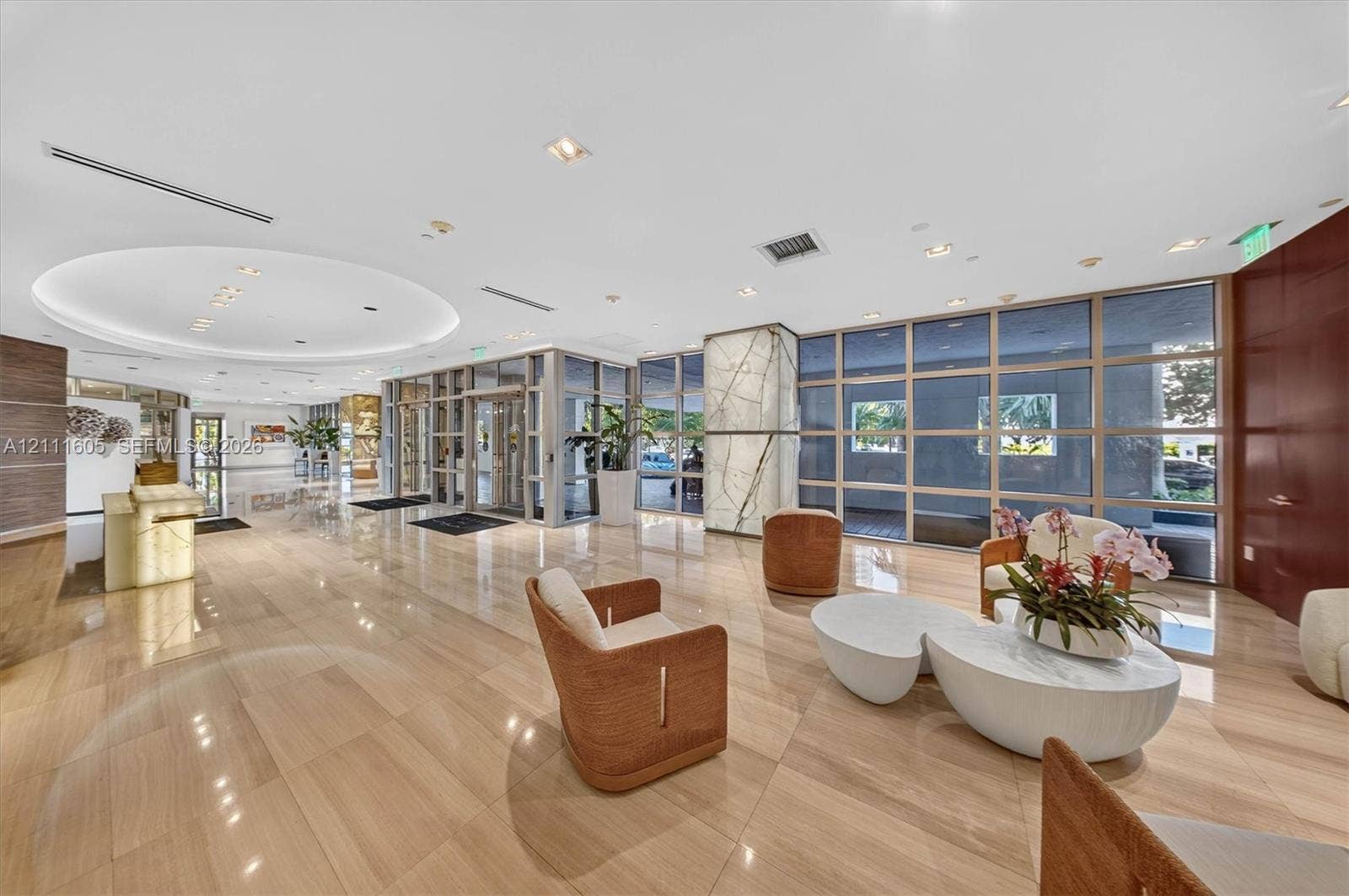 Lobby featuring polished stone flooring, recessed circular ceiling lighting, floor-to-ceiling glass panel walls, and a feature pillar with stone cladding