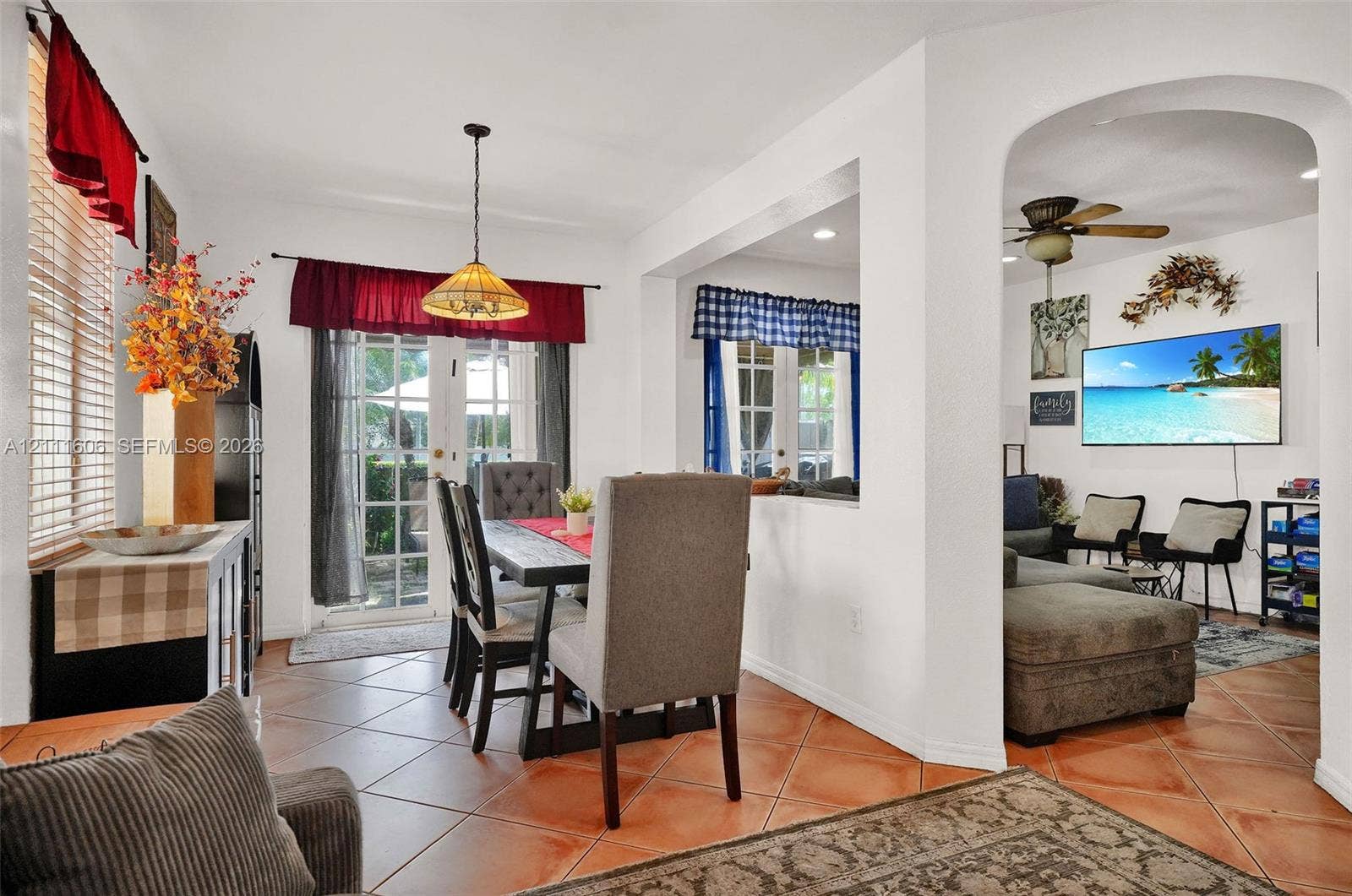 Ceramic tile flooring, arched wall opening, dual glass-paned doors, and pendant lighting