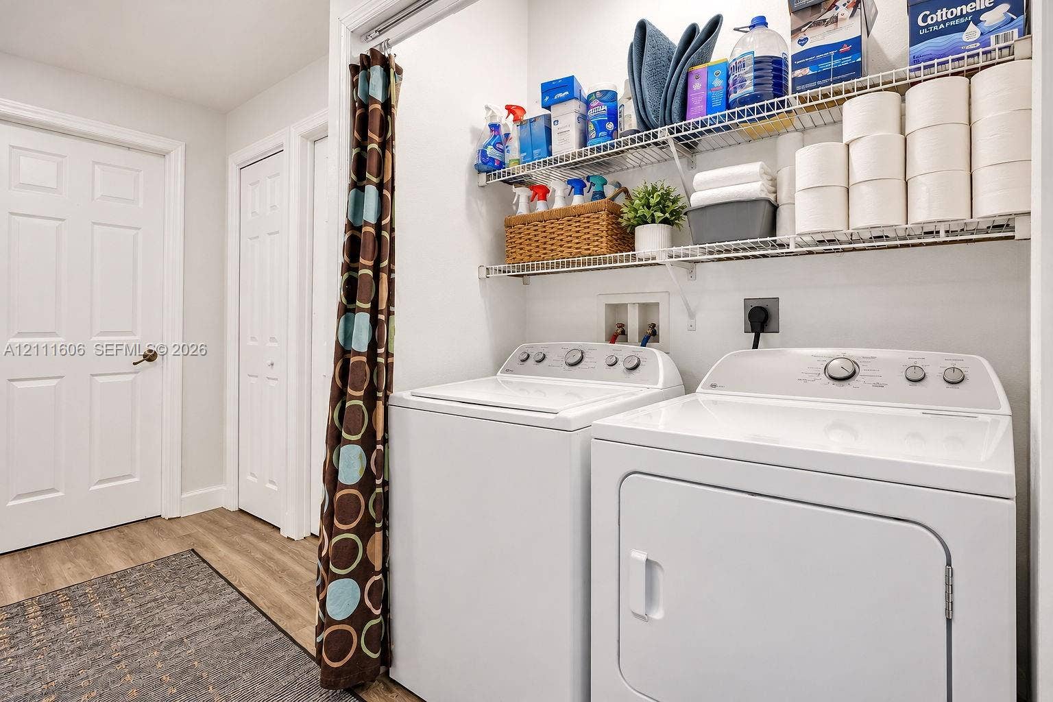Laundry area featuring wood-finish flooring, two multi-tiered wire storage shelves, and dedicated washer and dryer hookups