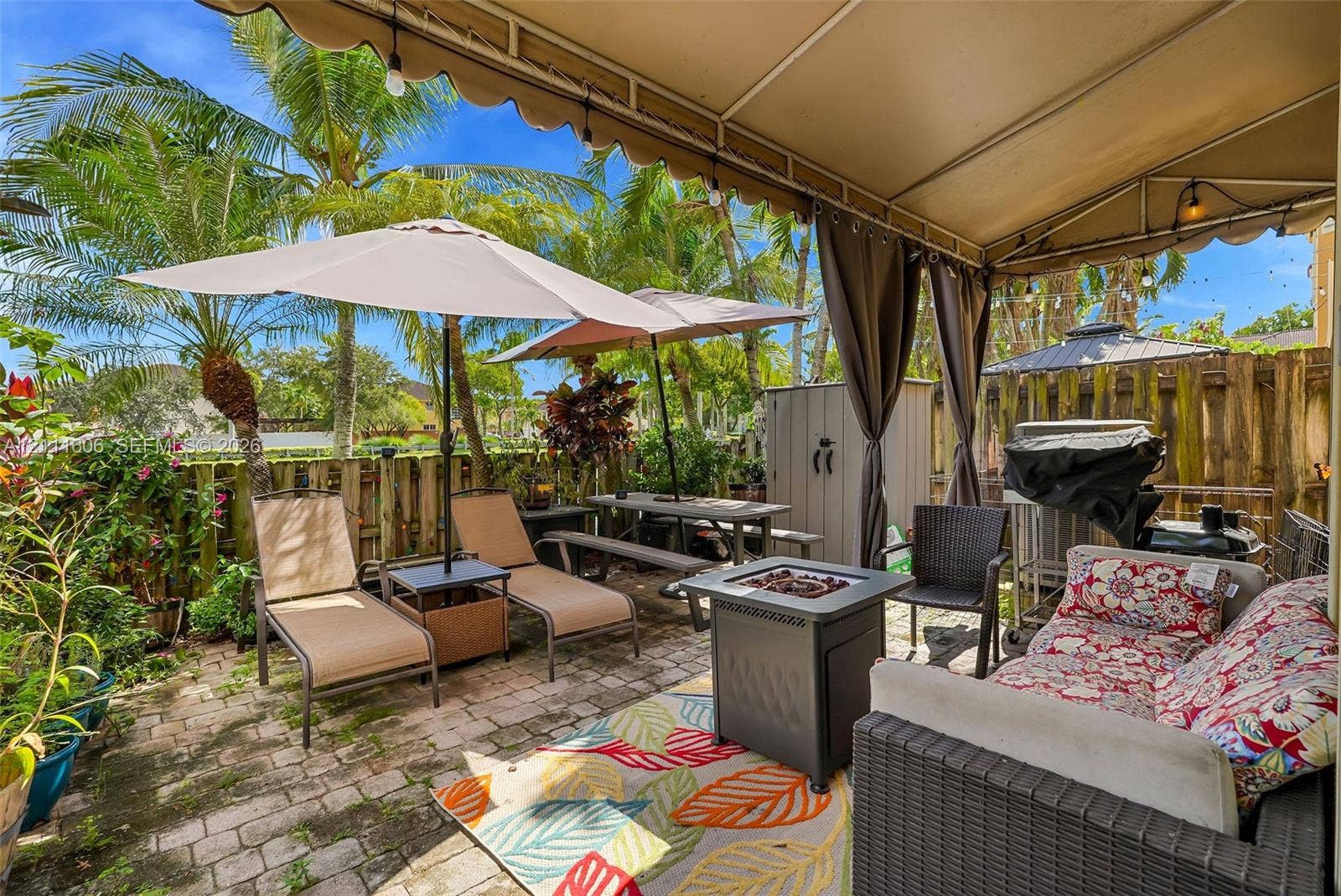 Covered patio featuring paver flooring, integrated fabric awning, and wood-style privacy fencing
