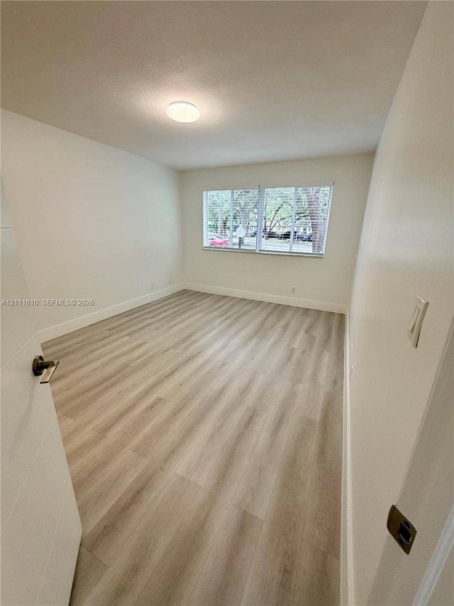 Interior room featuring wood-finish flooring, white walls, and a recessed ceiling light fixture