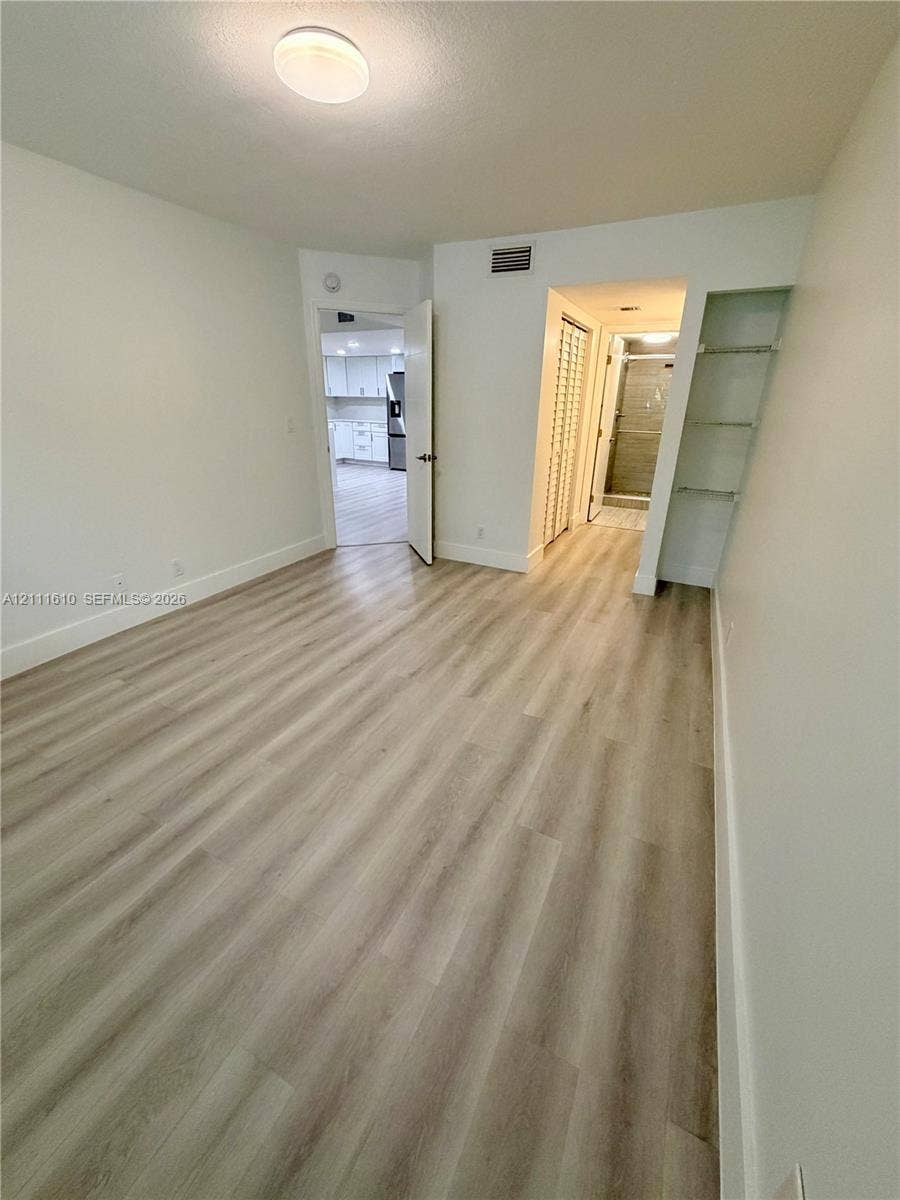 Room featuring wood-finish flooring, recessed flush-mount lighting, built-in open shelving, and a bifold closet door