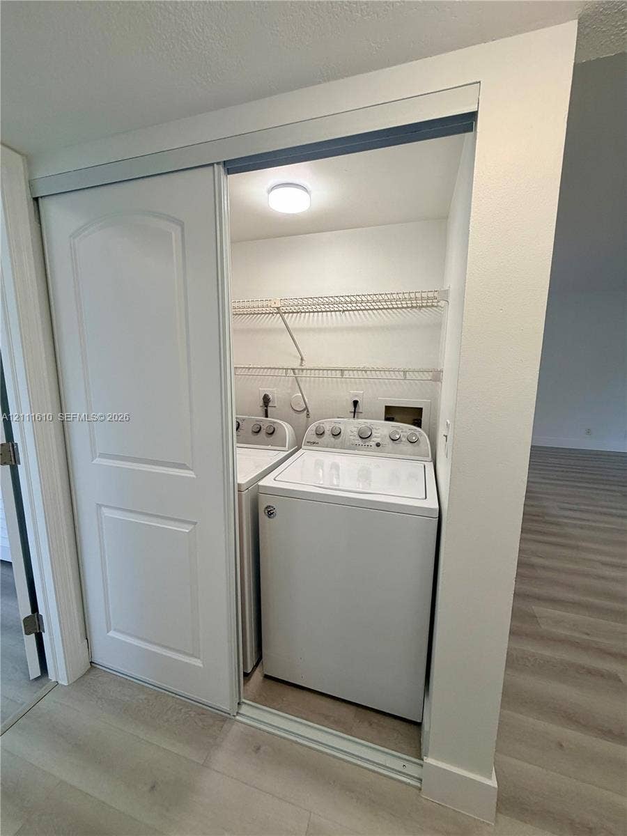 Laundry closet featuring sliding doors, white top-load washer and dryer, and integrated wire shelving