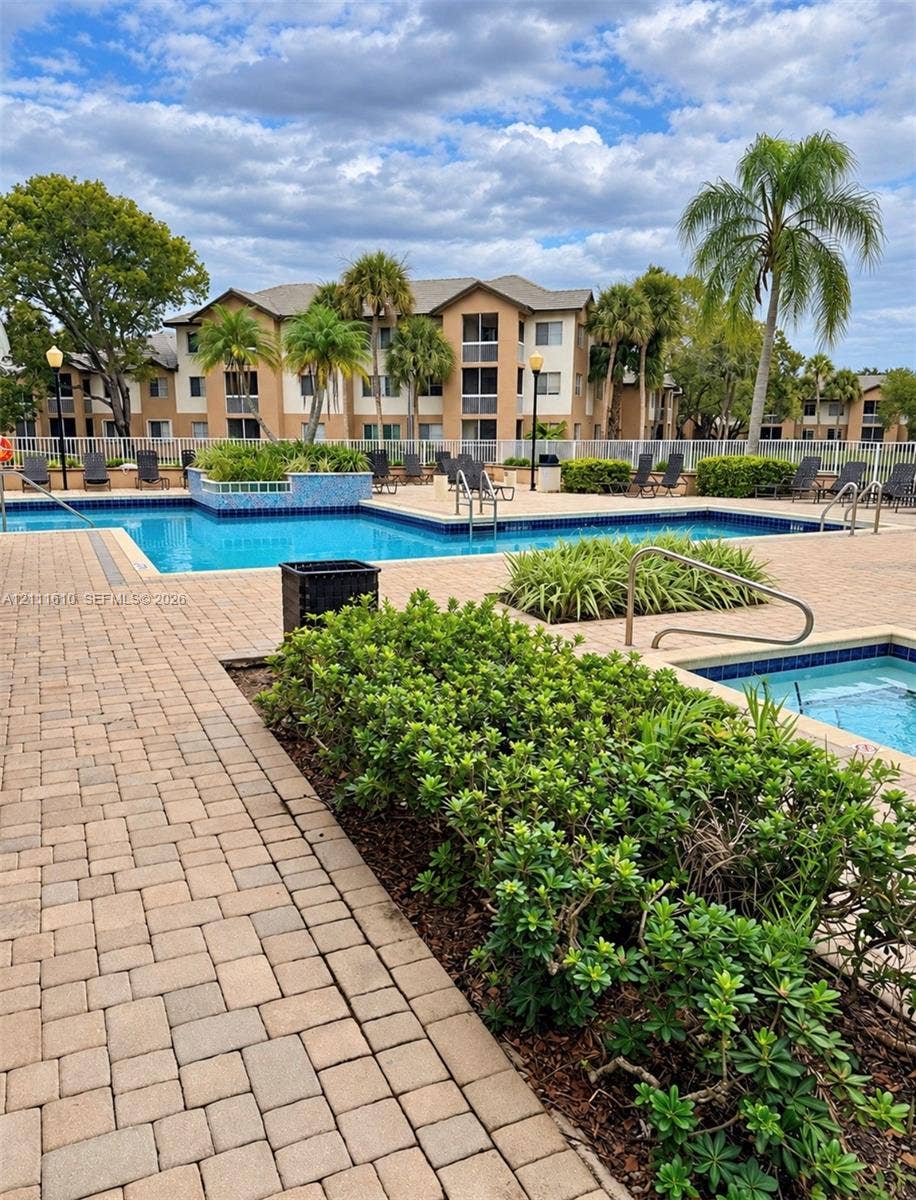 Outdoor swimming pool and spa featuring paver decking, built-in tiled water features, and manicured landscaping