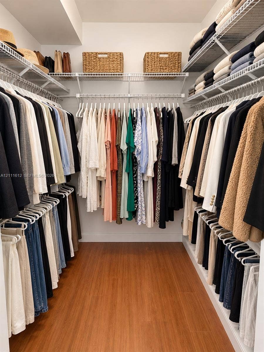 Walk-in closet featuring tiered wire shelving and wood-finish flooring
