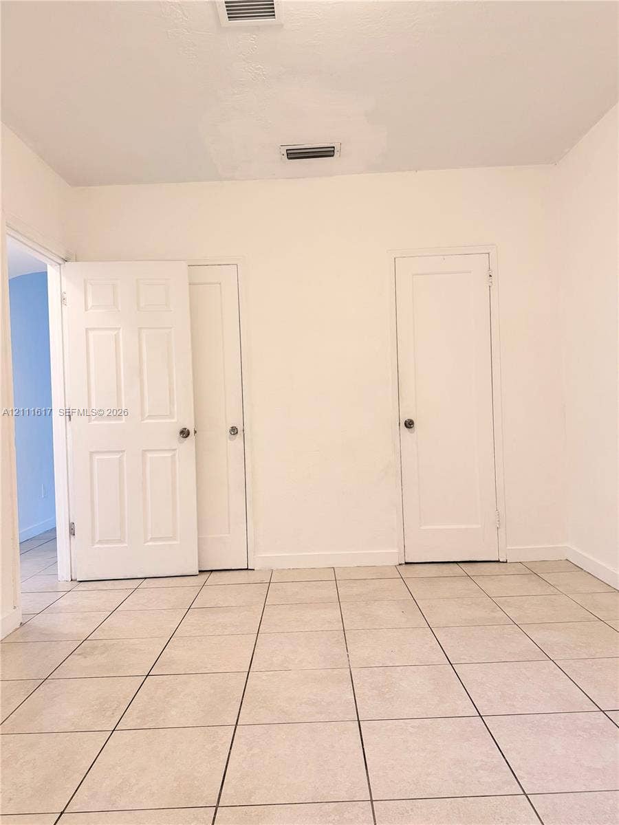 Interior space featuring neutral wall tones, large-format ceramic tile flooring, and multiple solid-core panel doors