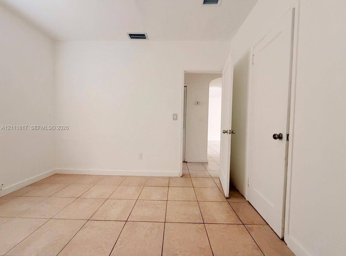 Neutral-toned tile flooring, solid-core interior doors with metallic hardware, and white-finished walls