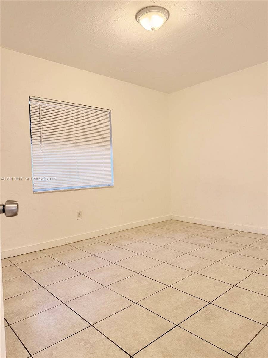Neutral-toned tile flooring, flush-mount dome ceiling lighting, and horizontal window blinds