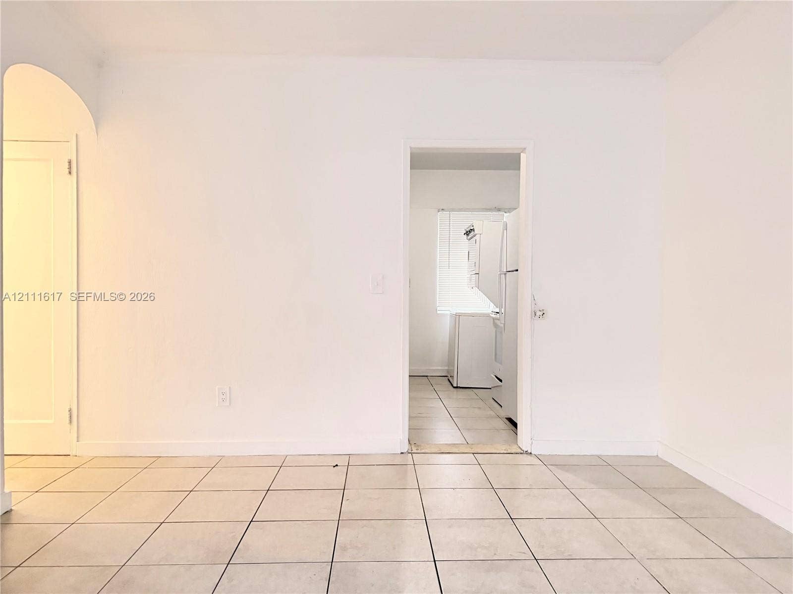 Neutral-toned ceramic tile flooring, arched doorway, and solid-core interior doors