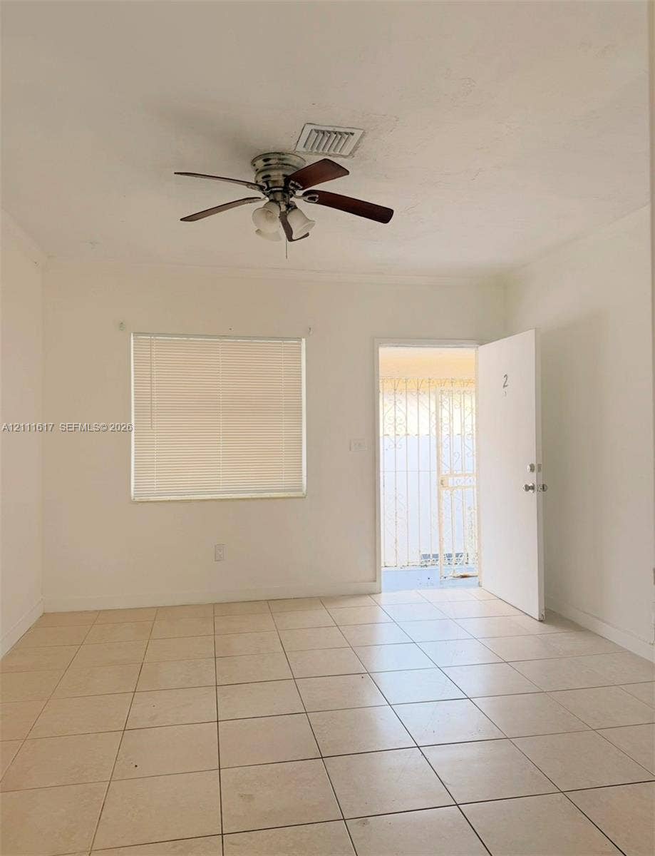 Neutral-toned tiled flooring, ceiling fan with integrated lighting, and window with attached horizontal blinds